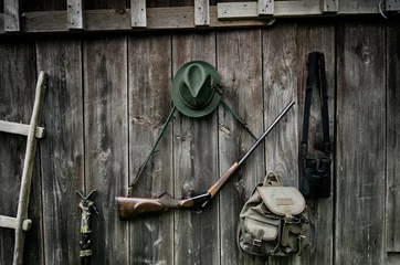 Stickers pour porte Chasser Équipement de chasseur professionnel pour la chasse. Fusil, chapeau, sac et autres sur fond noir en bois.