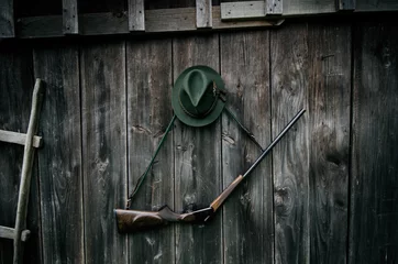 Papier Peint photo Chasser Équipement de chasseur professionnel pour la chasse. Fusil, chapeau, sac et autres sur fond noir en bois.