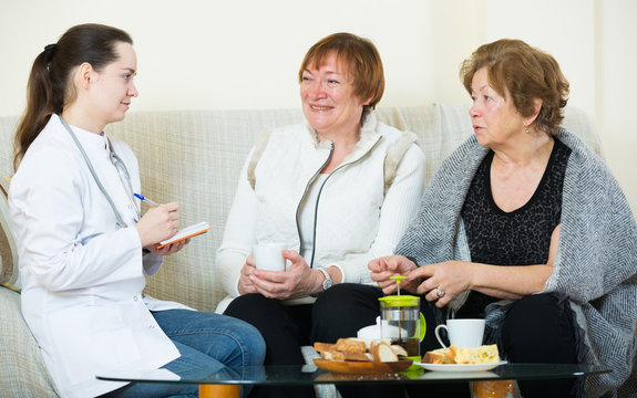 Two female pensioners discussing health problems with doctor