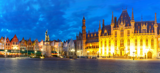 Fototapeta na wymiar Panoramic view of typical Flemish colored houses and statue of Jan Breydel and Pieter de Coninck on the Grote Markt or Market Square during evening blue hour, Bruges, Belgium