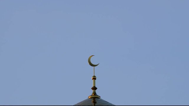 TimeLapse. The golden crescent on the minaret of the Islamic mosque on a heavenly blue background with white clouds. Close up.