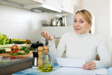 Happy housewife with documents in kitchen