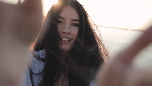 Young smiling woman holding camera showing tongue in sun beams, slow motion