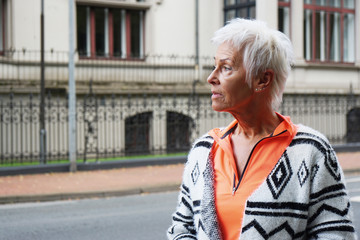sporty mature woman with trendy white short hair walking on street