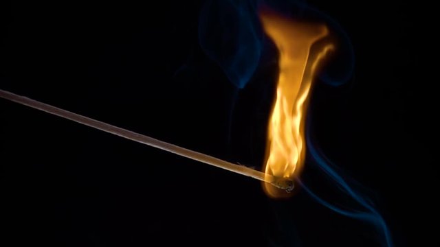 Burning match on a black background in slow motion