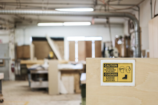 Interior Of A Woodworking Factory Showing A Sign For Safety Gear Regulations.