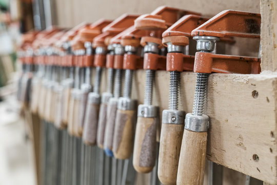 Close up of small bar clamps being used in a woodworking factory.