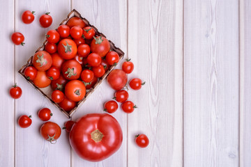 Ripe tomatoes, cherry in a basket on a white wooden background