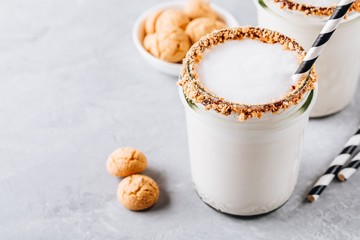 Vanilla milkshake with crispy cookies in glass mason jar on gray background