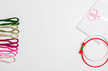 Embroidery outdoors. cross stitch, needlework accessories (needle, colored thread and scissors) on white background, top view, Flatley.