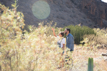 Couple standing in tall brown grass and pointing