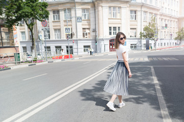 Summer sunny lifestyle fashion portrait of young stylish hipster woman walking on the street,