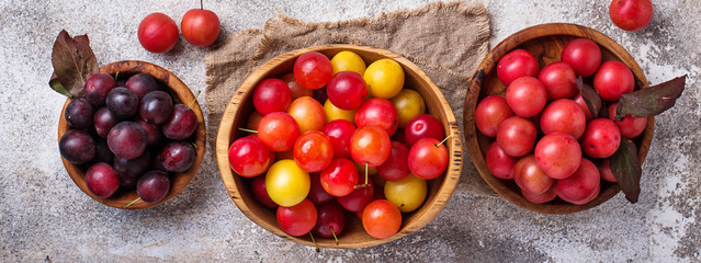 Various type of cherry-plum in wooden bowls 