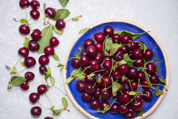 Top view of ripe red cherry in the blue plate and on the table