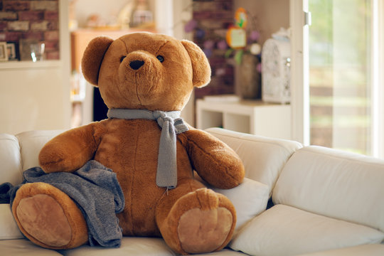 huge teddy bear is sitting on the couch, waiting for someone to cuddle him