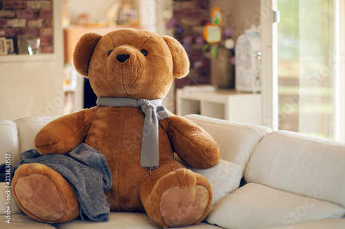 huge teddy bear is sitting on the couch waiting for someone to