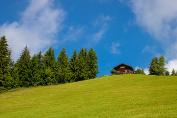 Old wooden hut on the top of a mountain and green meadow in the austrian alps