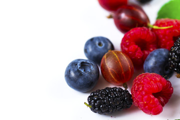 Close-up arrangement mixed, assorted berries including blackberries, strawberry, blueberry, raspberries and fresh leaf on white