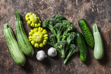 Broccoli, zucchini, squash, garlic, cucumbers - fresh organic vegetables on a wooden background, top view. Flat lay, copy space