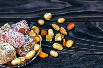 Traditional oriental sweets and traditional Turkish tea on a dark wooden background. Turkish desert-Rahat locum.