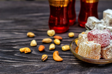 Traditional oriental sweets and traditional Turkish tea on a dark wooden background. Turkish desert-Rahat locum.