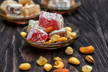 Traditional oriental sweets and traditional Turkish tea on a dark wooden background. Turkish desert-Rahat locum.