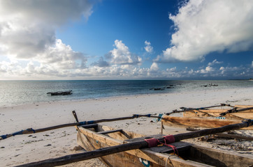 Traditional wooden fishing boats in the East of Zanzibar. Clouds over the Indian Ocean. Gorgeous sunrise over the ocean.
