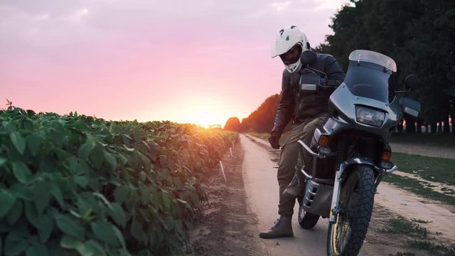 Biker Man in leather jacket ride outdoor with his Adventure Motorcycle enjoy this moment, off road travel concept, enduro rider equipment, extreme lifestyle, copy space, fog light, beautiful sunset