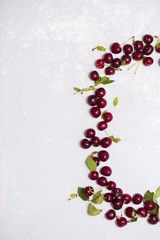 A few ripe cherries on a gray textured background, top view