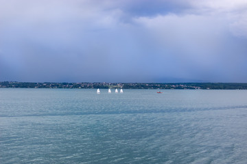 Row of sailboats in sea against sky
