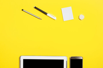 felt pen, pencil, rubber and paper stickers lying in front of smartphone and tablet pc at the...