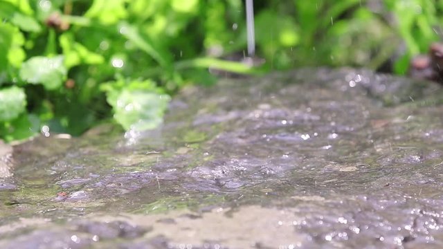 Drops of rain fall on the granit stone in the garden. Drops of water drip onto wet stone. Loop, dynamic scene, toned video.