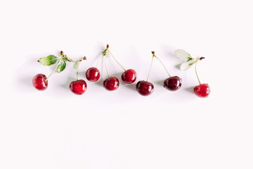 Obraz na płótnie Canvas Cherry pattern. Ripe cherry berries and leaves isolated on white background. Berry summer background. Flat lay, top view, copy space 
