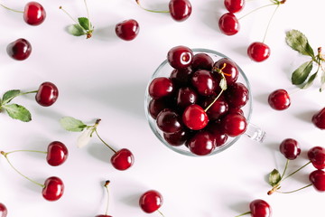 Juicy cherry in a glass bowl. Ripe cherry berries and leaves isolated on white background. Berry summer background. Flat lay, top view, copy space 