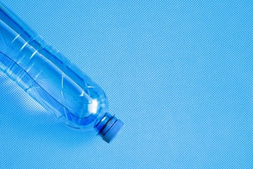 Water bottle on light blue background of yoga mat. Concept of healthy lifestile. Flat lay, top view, copy space 