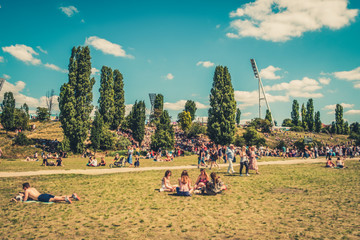 Cityscape blur concept - People enjoying sunny summer day on meadow in crowded Park (Mauerpark) in...