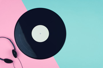 top view of a long play vinyl record or LP with a black on-ear headphone on the pink and blue...