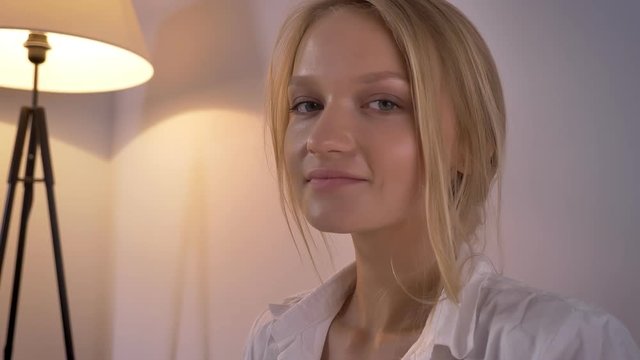 Young sexy blonda lady in lingerie and shirt is sitting on sofa, watching at camera, relax concept