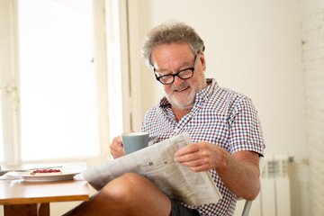 happy old man reading the newspaper while having breakfast
