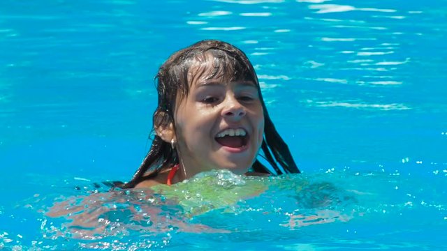 Child in the pool. A little girl is swimming in an outdoor pool.