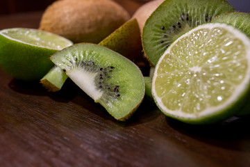 Sliced kiwi with lime on a dark brown wooden table