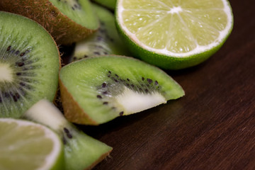 Fototapeta na wymiar Sliced kiwi with lime on a dark brown wooden table