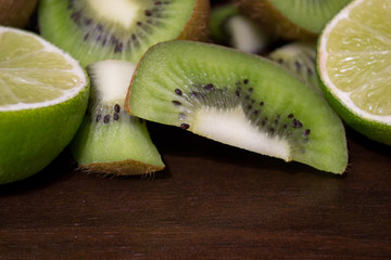 Sliced kiwi with lime on a dark brown wooden table