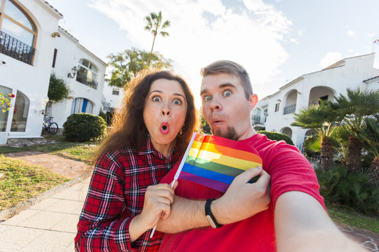 Gay and lesbian friendship holding rainbow flag
