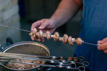 Man prepares marinated mushrooms for cooking on the grill