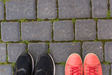 On the paving stones there are two pairs of shoes, top view