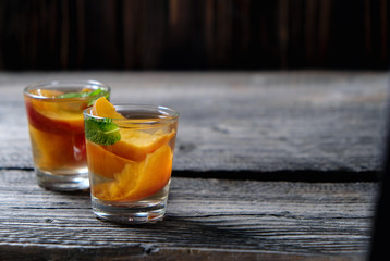 Peach Tea with pieces of fruit and mint on a wooden background,