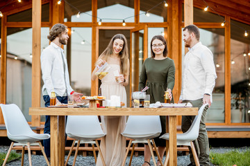 Four friends enjoying evening time together drinking beer on the backyard of the modern country house