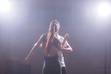 Skillful dancers performing in the dark room under the concert light and smoke. Sensual couple performing an artistic and emotional contemporary dance