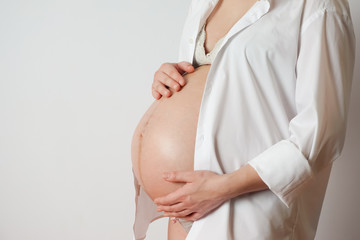 pregnant woman on white background touches belly